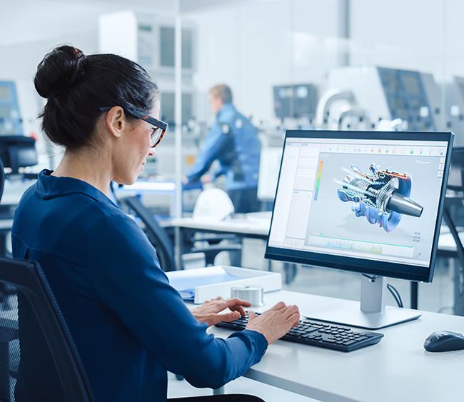 A woman sitting in front of a computer in an office environment. Photo.