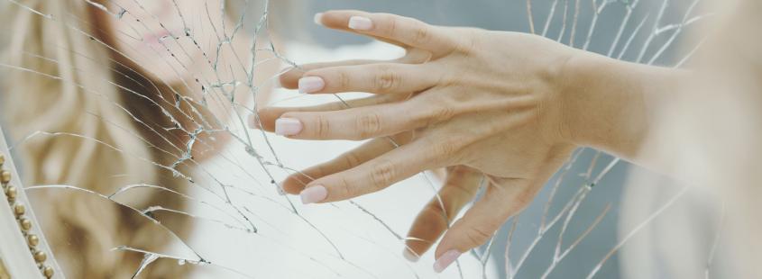 A woman`s hand on a broken mirror.