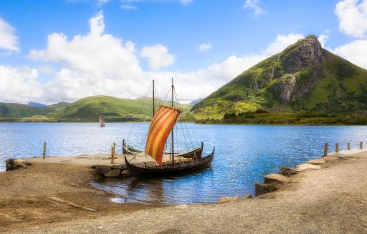 A small vikng ship at shore in a bay. 