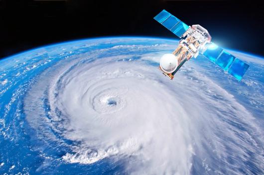 A sattelite monitors a weather system on Earth below.