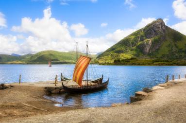A small vikng ship at shore in a bay. 