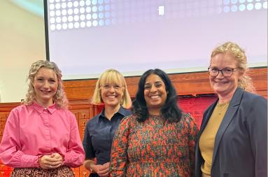 Four women smiling together on stage in front of a presentation screen reading "Borealis".
